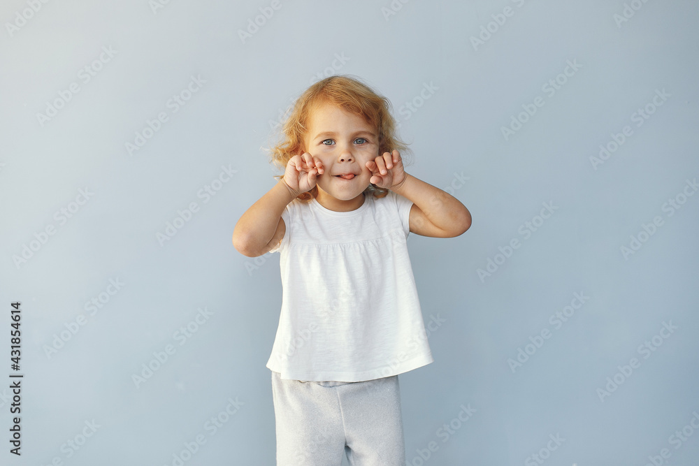 Cute little girl sitting in a studio on a blue background Cute little girl sitting in a studio on a blue background