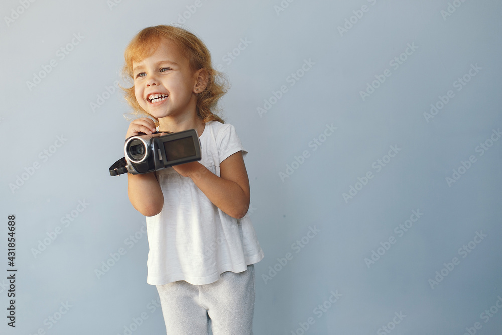 Fototapeta premium Cute little girl sitting in a studio on a blue background