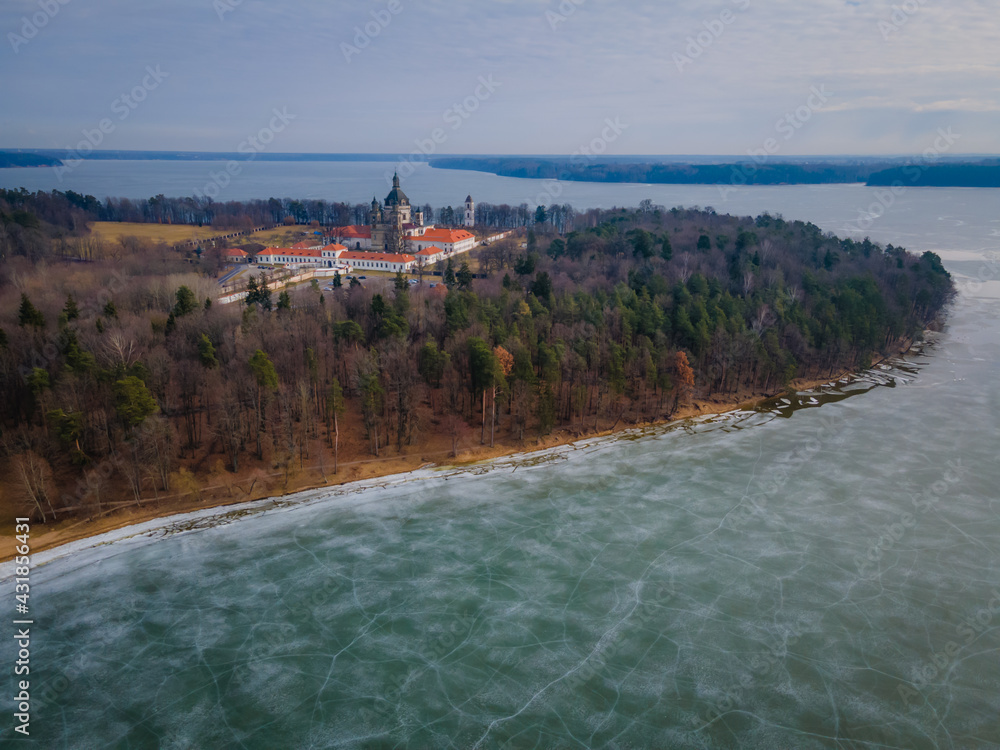 Aerial winter view of Pazaislis monastery in Kaunas, Lithuania. With icy Kaunas lake with cracked ice around the cape