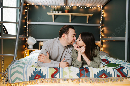 Passionate middle aged couple in love snogging in bed, looking at each other. Lying next to each other on a blanket under a garland.
