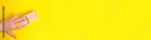Photos Man hand was caught in a mousetrap on a yellow background
