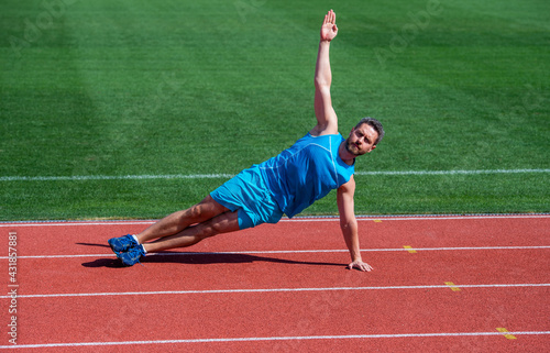 athlete train his core muscles. man doing stretching exercise on stadium. fitness gym outdoor. Full of energy. athletic guy training. sport. male strength and power. sportsman in side plank