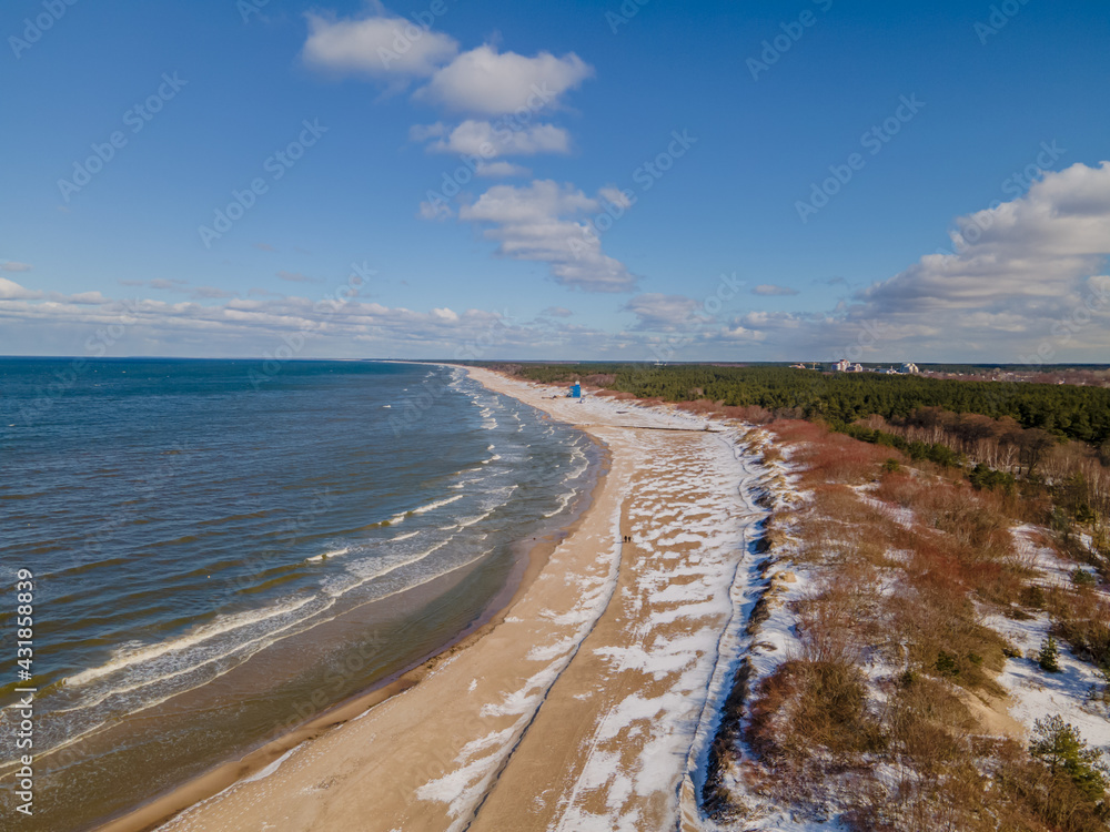Aerial view of snowy Baltic sea coastline with dunes in one side and sea in another