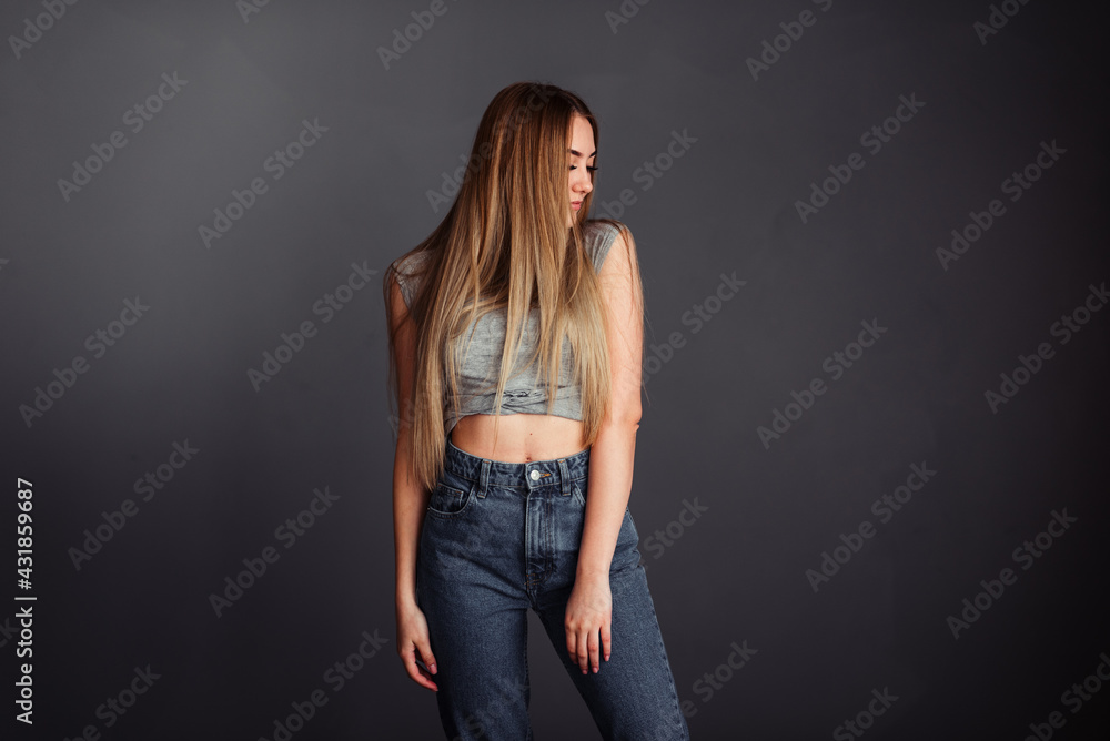 A girl with long hair looks stretched up on a gray background without retouching. A girl with long hair looks stretched up on a gray background without retouching.