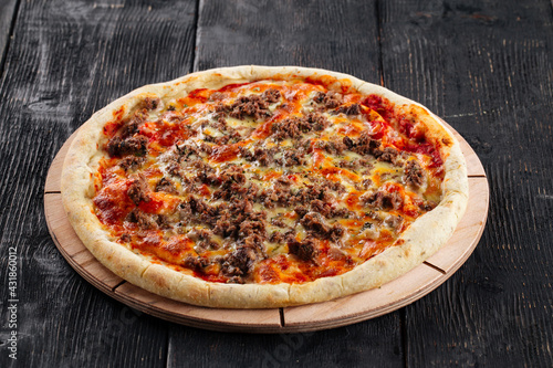 Pizza with minced meat and tomato sauce on the dark wooden background
