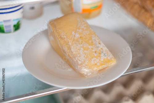 Cuadro en lienzo Moldy cheese wrapped in cling film in the refrigerator