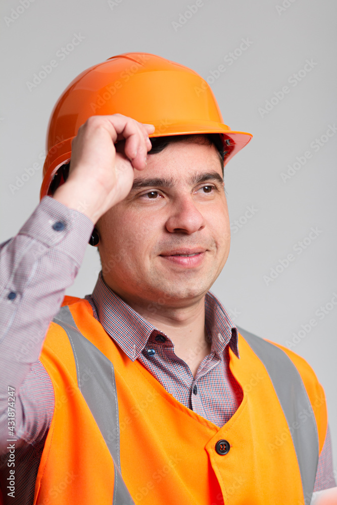 portrait of successful young construction worker in hard hat on grey studio background greeting portrait of successful young construction worker in hard hat on grey studio background greeting