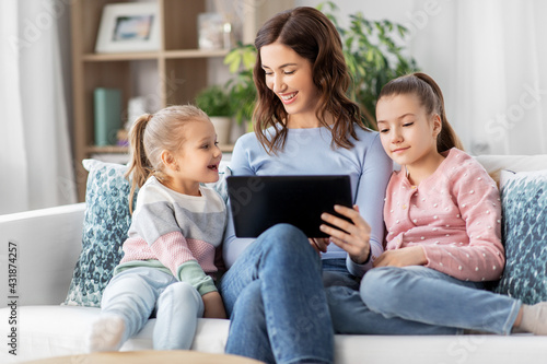 people, family and technology concept - happy mother and two daughters with tablet pc computer at home