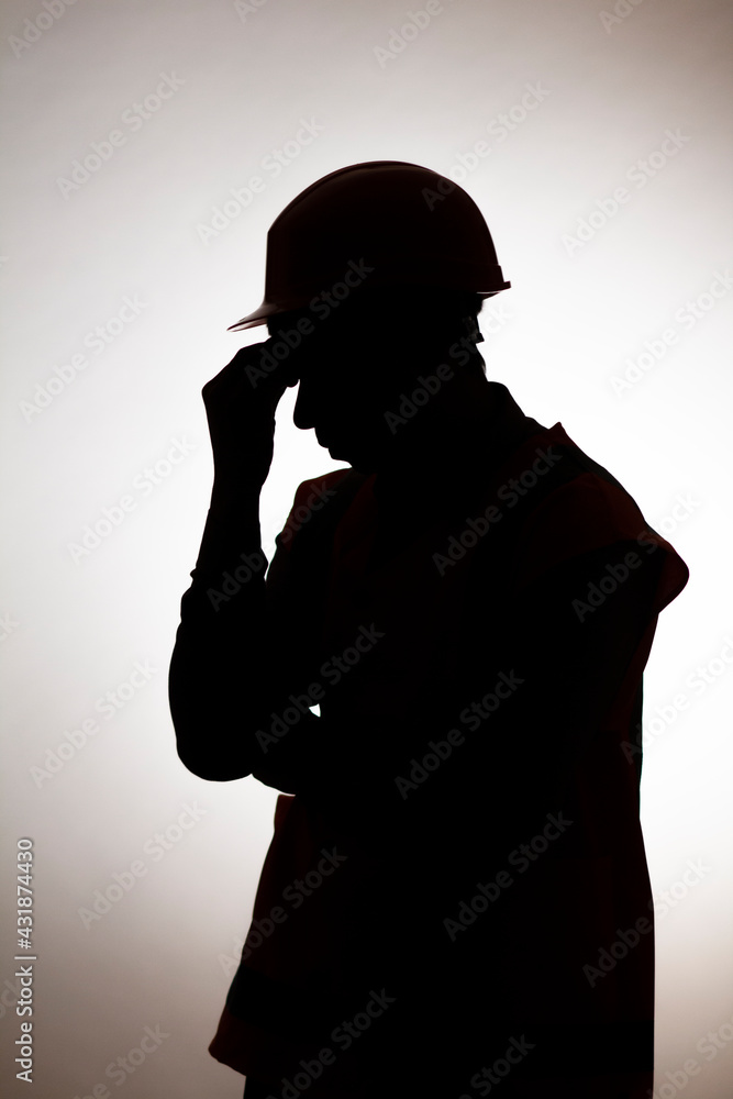 silhouette of tired builder bowed head in emotional stress on depressive isolated background, male unemployment concept