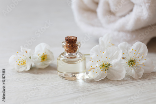 apricot or cherry essential oil or perfume glass bottle with fresh flowers river pearls on wooden background, spa