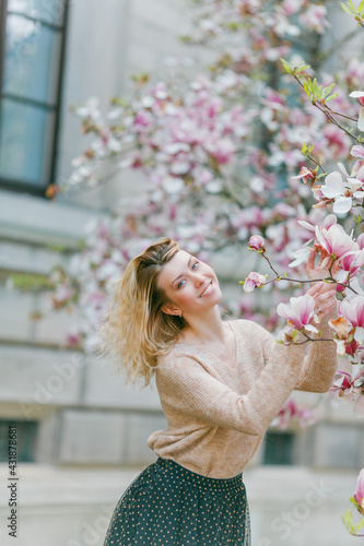 Beautiful young blonde near a blossoming Magnolia tree. Spring.
