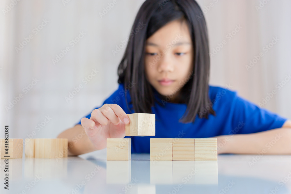 Girl playing wood cube educational toys in the living room at home, Asian kid playing with a toy block designer on the table, Kids learning concepts Girl playing wood cube educational toys in the living room at home, Asian kid playing with a toy block designer on the table, Kids learning concepts