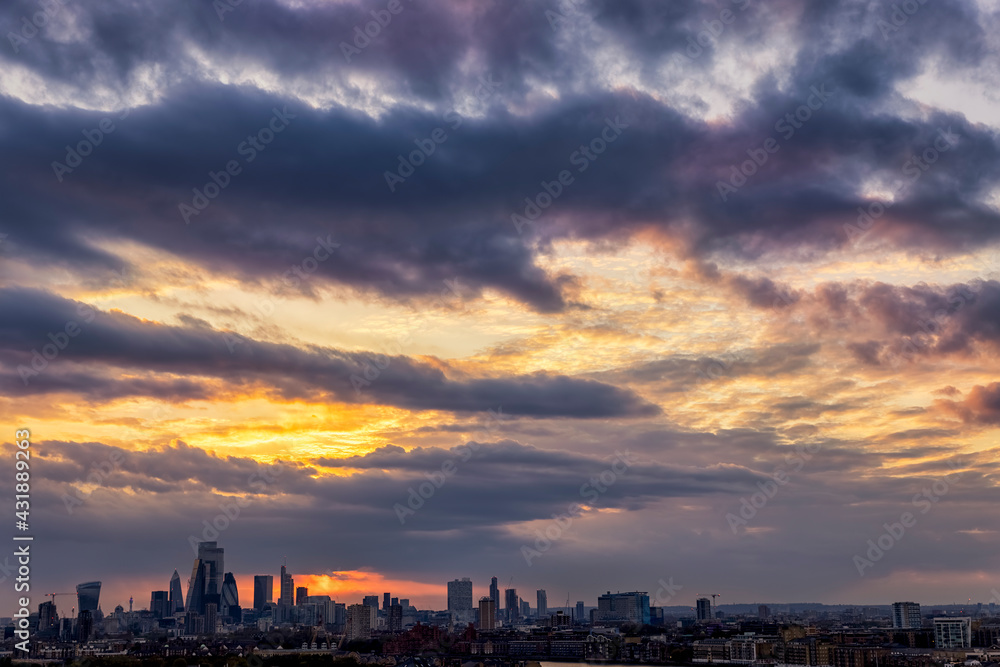 A sunset sky with pink and orange clouds above a city skyline