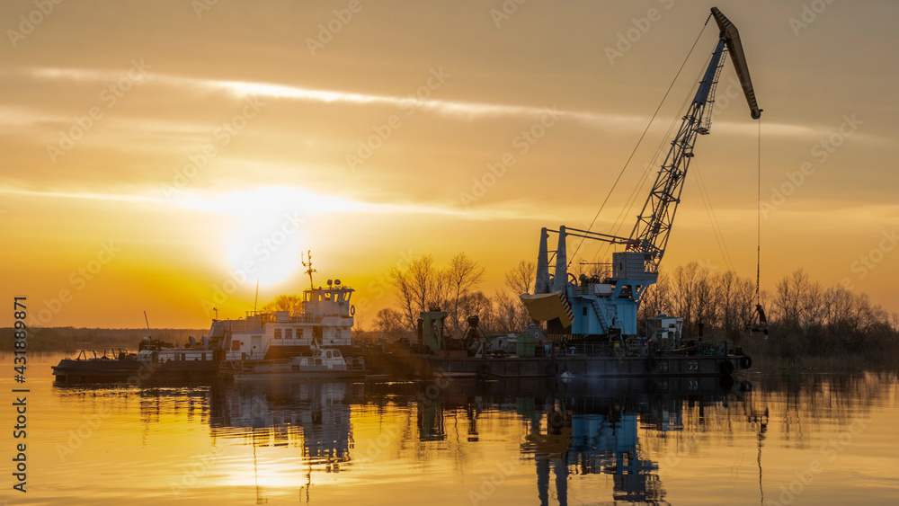 Dredger is working to deepen the fairway on the river. Cleaning and deepening by a dredger on the river. Sunset on the river. Industrial concept.