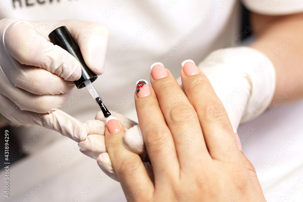 Manicure. Covering natural nails with gel polish, white french coat and nail design in a beauty salon by a manicure master. Close-up Manicure. Covering natural nails with gel polish, white french coat and nail design in a beauty salon by a manicure master. Close-up