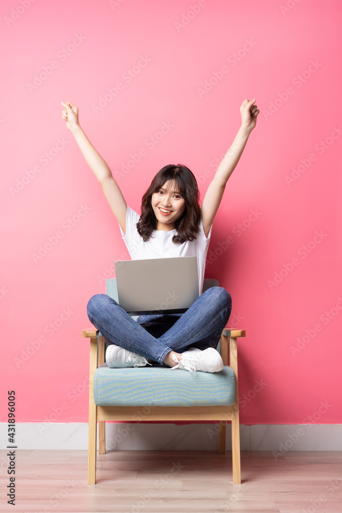 Asian woman sitting on sofa using laptop with happy expression Asian woman sitting on sofa using laptop with happy expression