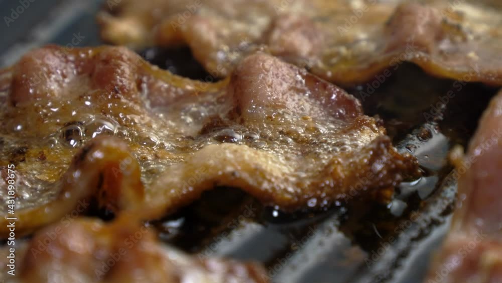 A close up of bacon frying on a cast iron grill A close up of bacon frying on a cast iron grill