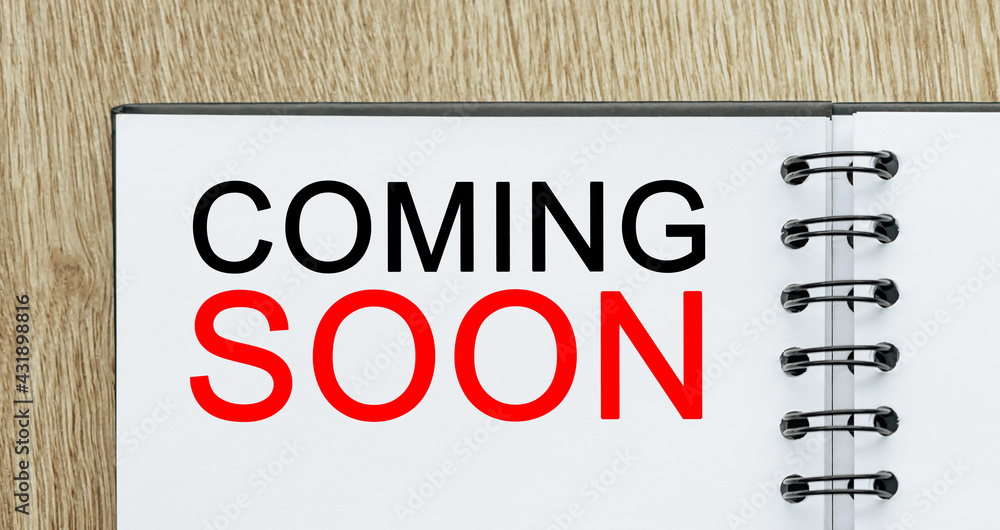 Notepad with text COMING SOON on wooden deskt. Business and finance concept Notepad with text COMING SOON on wooden deskt. Business and finance concept