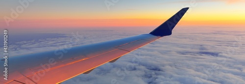 Golden sunset sky with fluffy ornamental cumulus clouds, panoramic view from an airplane, wing close-up. Dreamlike cloudscape. Travel, tourism, vacations, weekend, freedom, peace, hope concepts
