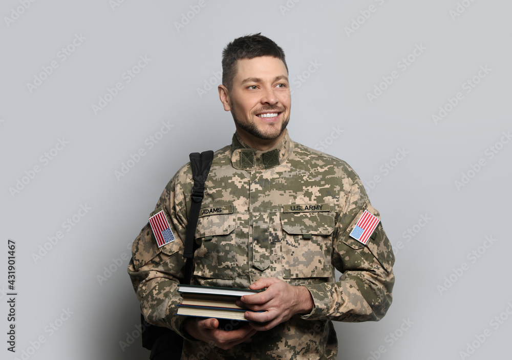 Cadet with backpack and books on light grey background. Military education Cadet with backpack and books on light grey background. Military education