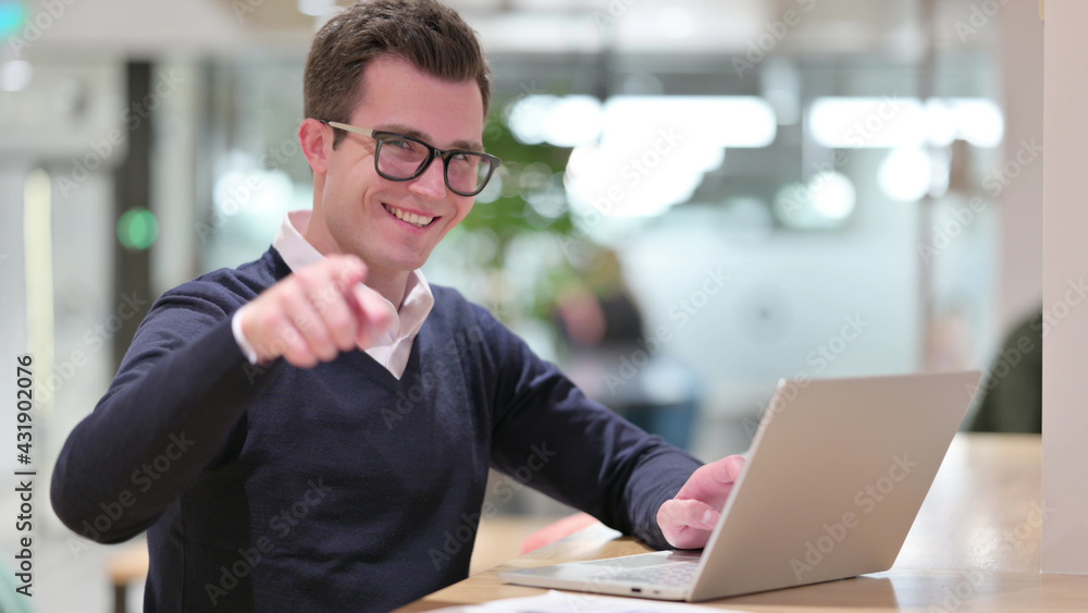 Young Businessman with Laptop Pointing at the Camera Young Businessman with Laptop Pointing at the Camera
