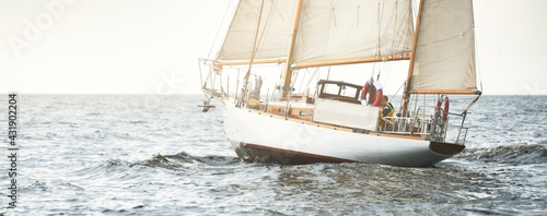 Old expensive vintage two-masted sailboat (yawl) close-up, sailing in an open sea during the storm. Sport, cruise, tourism, recreation, transportation, nautical vessel. Panoramic view, seascape