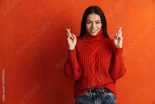 Young hispanic woman smiling while holding fingers crossed