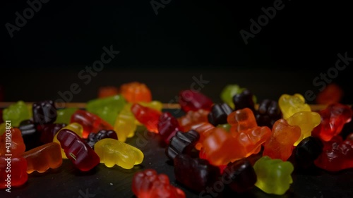 Bear shape jelly beans candies falling down. Black background, macro,150 fps