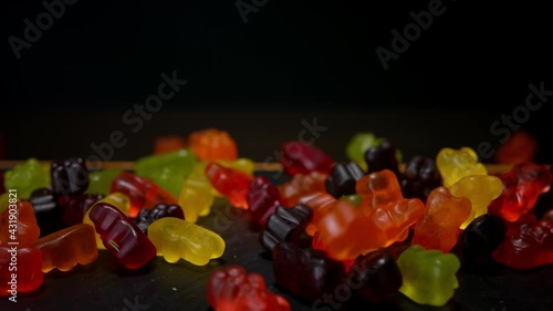 Bear shape jelly beans candies falling down. Black background, macro,150 fps photo