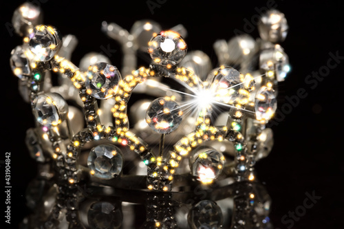 Gold crown with shiny stones on a black background.