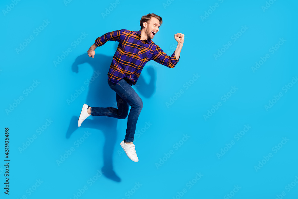 Photo of funky hurrying young gentleman dressed checkered shirt smiling jumping running isolated blue color background
