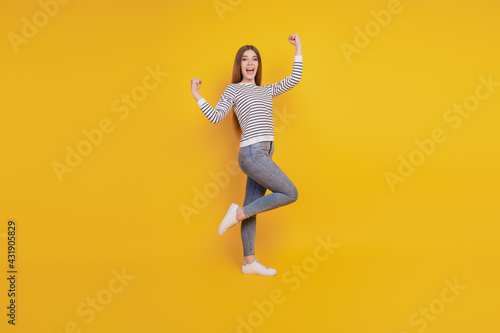 Portrait of crazy cheerful lady raise fists celebrate victory on yellow background