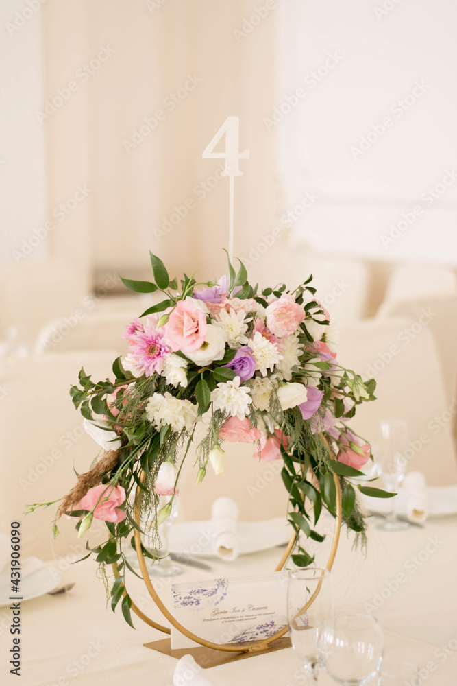 Centerpiece made of green leaves and fresh flowers stands on the dinner table. Wedding day. Fresh flowers decorations. Centerpiece made of green leaves and fresh flowers stands on the dinner table. Wedding day. Fresh flowers decorations.
