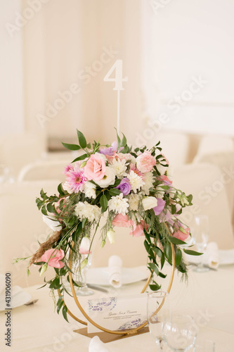 Centerpiece made of green leaves and fresh flowers stands on the dinner table. Wedding day. Fresh flowers decorations.
