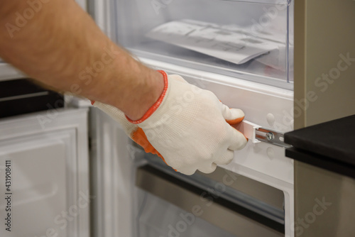 A worker is fixing the built-in refrigerator in the kitchen furniture. photo