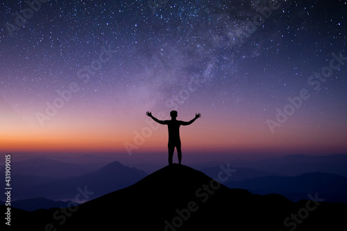 Silhouette of young traveler and backpacker watched the star and milky way alone on top of the mountain. He Stand with both hands raised enjoyed traveling and was successful.