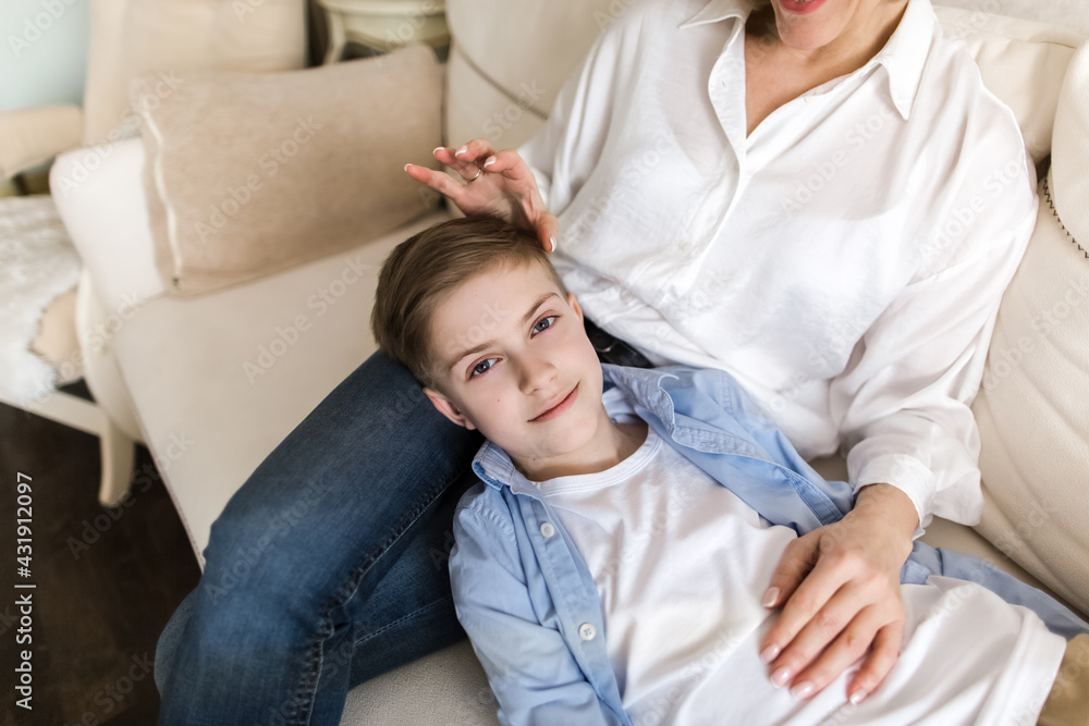 The boy lies on the lap of the woman and looks directly into the camera. The boy lies on the lap of the woman and looks directly into the camera.