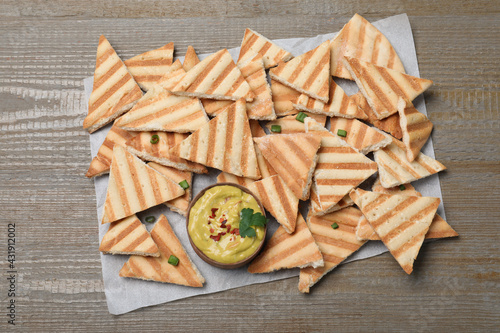 Delicious pita chips and hummus on wooden table, top view © New Africa