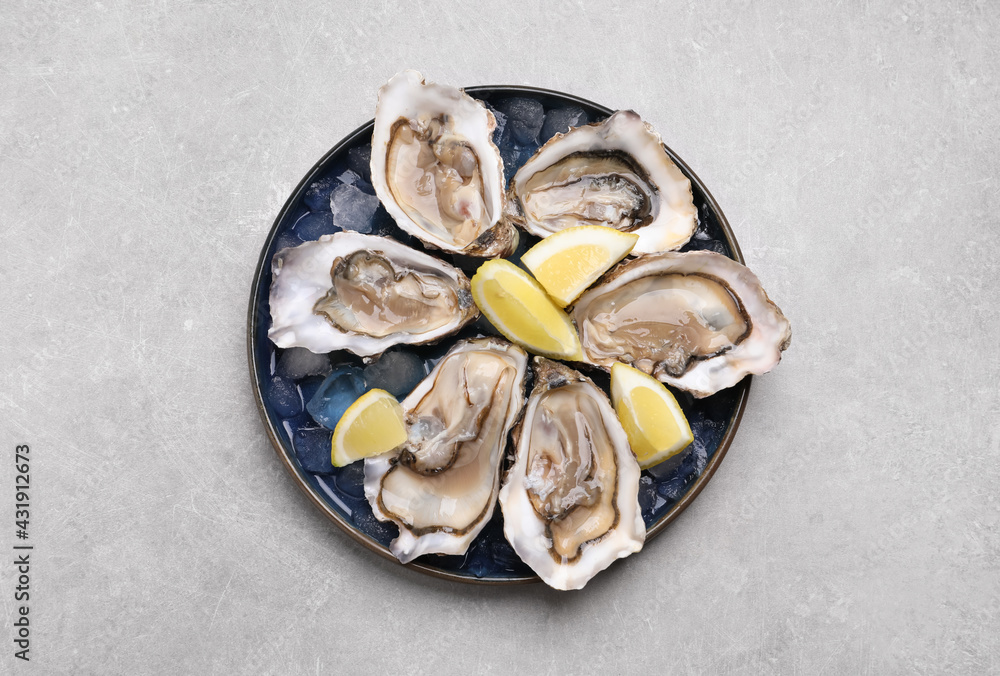 Delicious fresh oysters with lemon slices on light grey table, top view Delicious fresh oysters with lemon slices on light grey table, top view