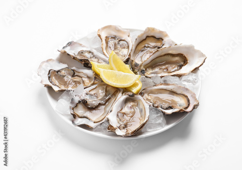 Delicious fresh oysters with lemon slices isolated on white