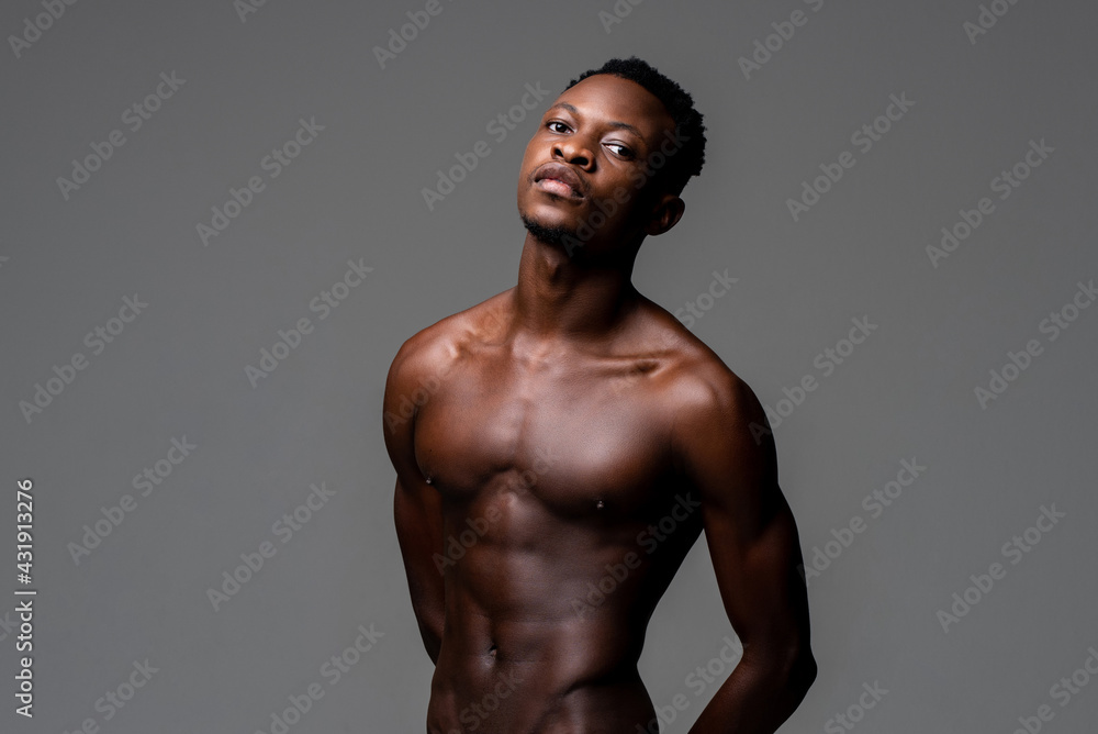 Waist up studio portrait of shirtless young lean fit African man in isolated light gray background Waist up studio portrait of shirtless young lean fit African man in isolated light gray background