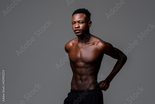 Studio shot portrait of shirtless fit young handsome African man in isolated gray studio background