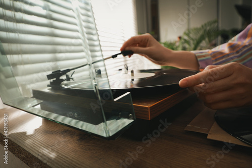 Young woman using turntable at home, closeup