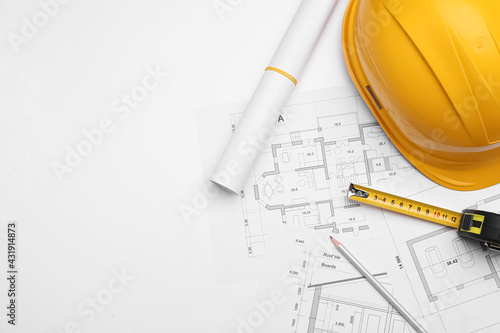 Flat lay composition with blueprints and hardhat on white background. Space for text