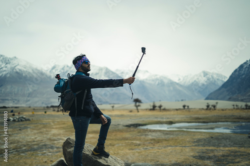 Young and handsome male travel blogger recording a video for vlog with his Go Pro action camera, making vlog for youtube.