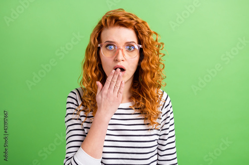 Photo of shiny excited young lady dressed striped clothes glasses arm cover mouth isolated green color background