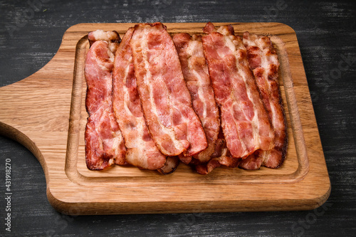 Quadro em tela Hot fried bacon on a black background, deliciously
