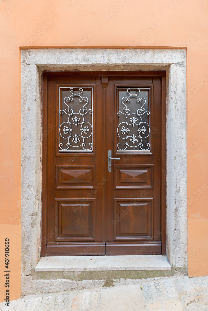 brown frame and panel door, surrounded by weathered concrete, light orange house front brown frame and panel door, surrounded by weathered concrete, light orange house front