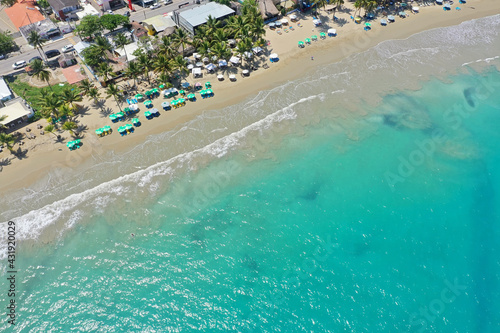 Aerial shot of the turquoise beach with buildings in Bukit Merese at Kuta, Indonesia photo