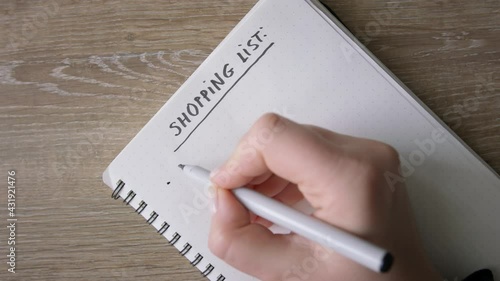 Female hands listing base products in shopping list. Top view, close up